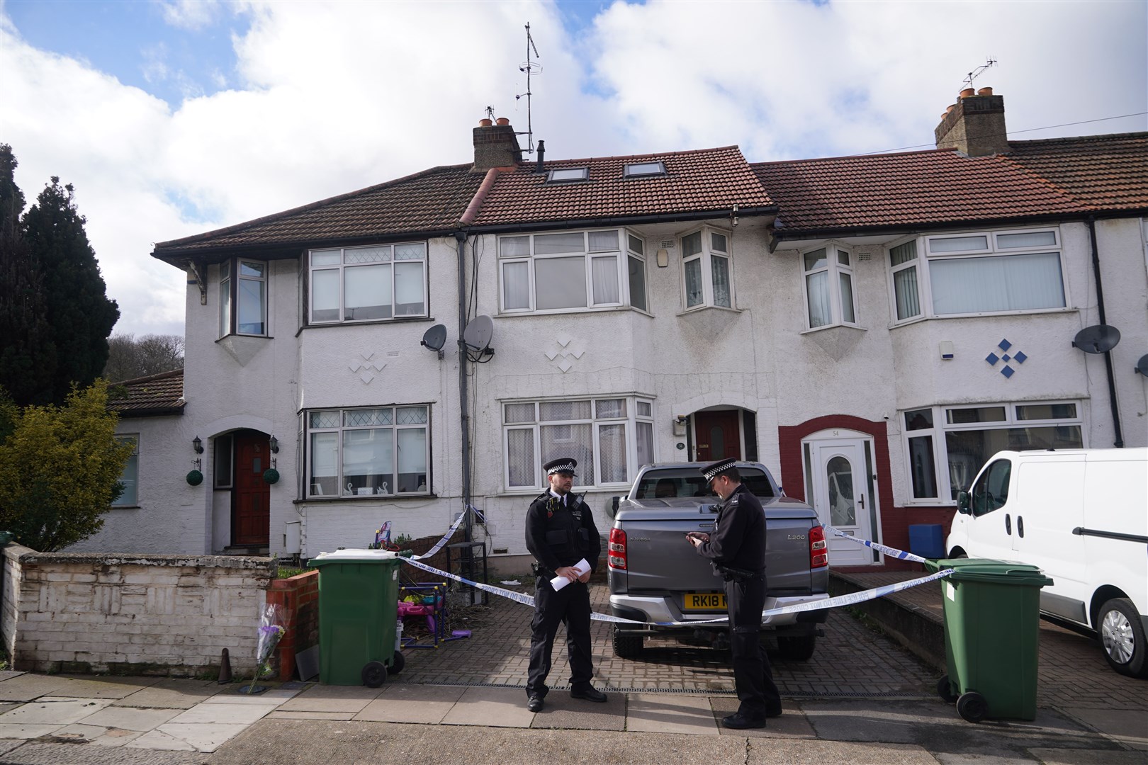 Police officers stand outside the house where the bodies were found (Yui Mok/PA)