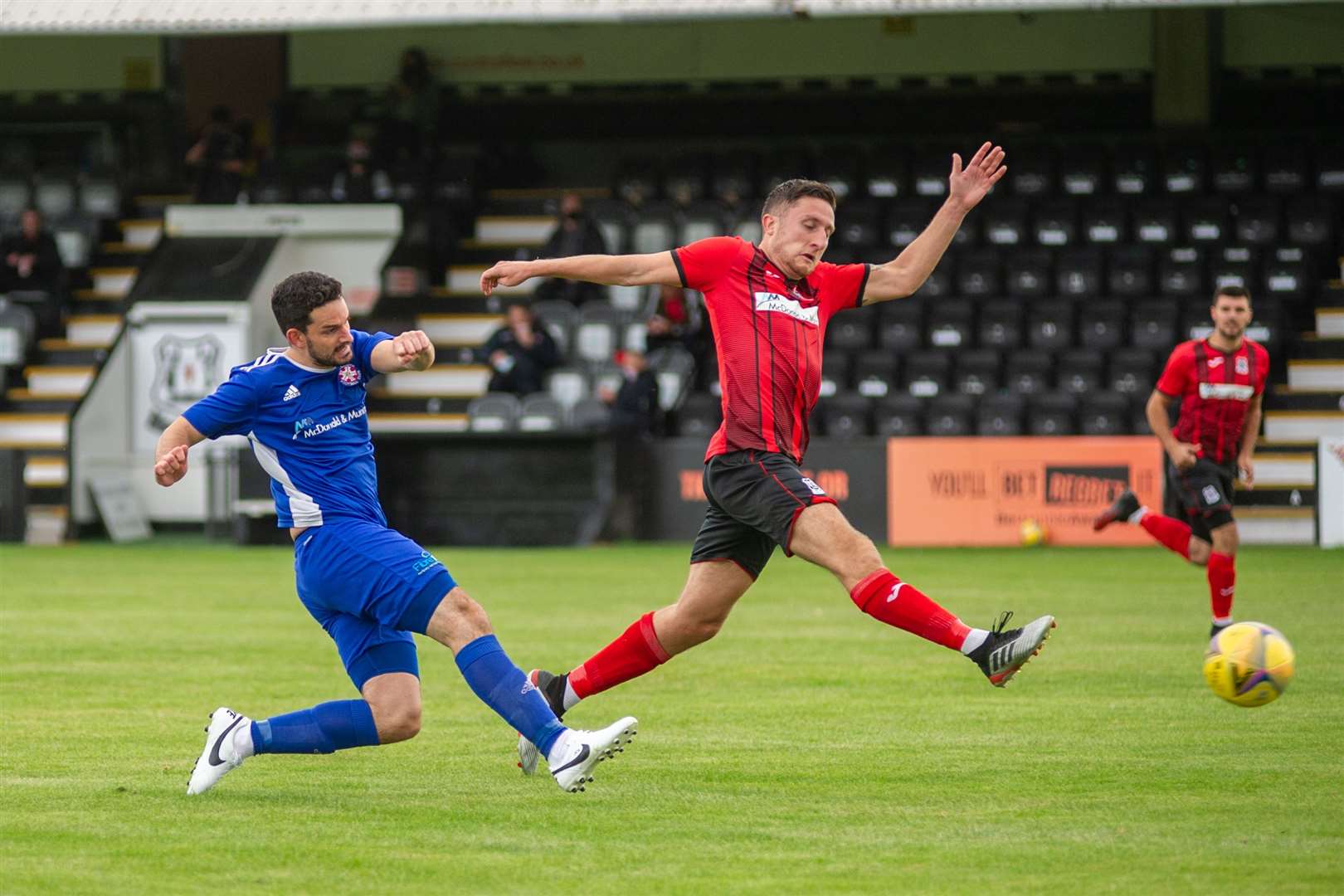 Elgin City centre back Stephen Bronsky tries to block this effort from Lossiemouth forward Martin Charlesworth. Picture: Daniel Forsyth..