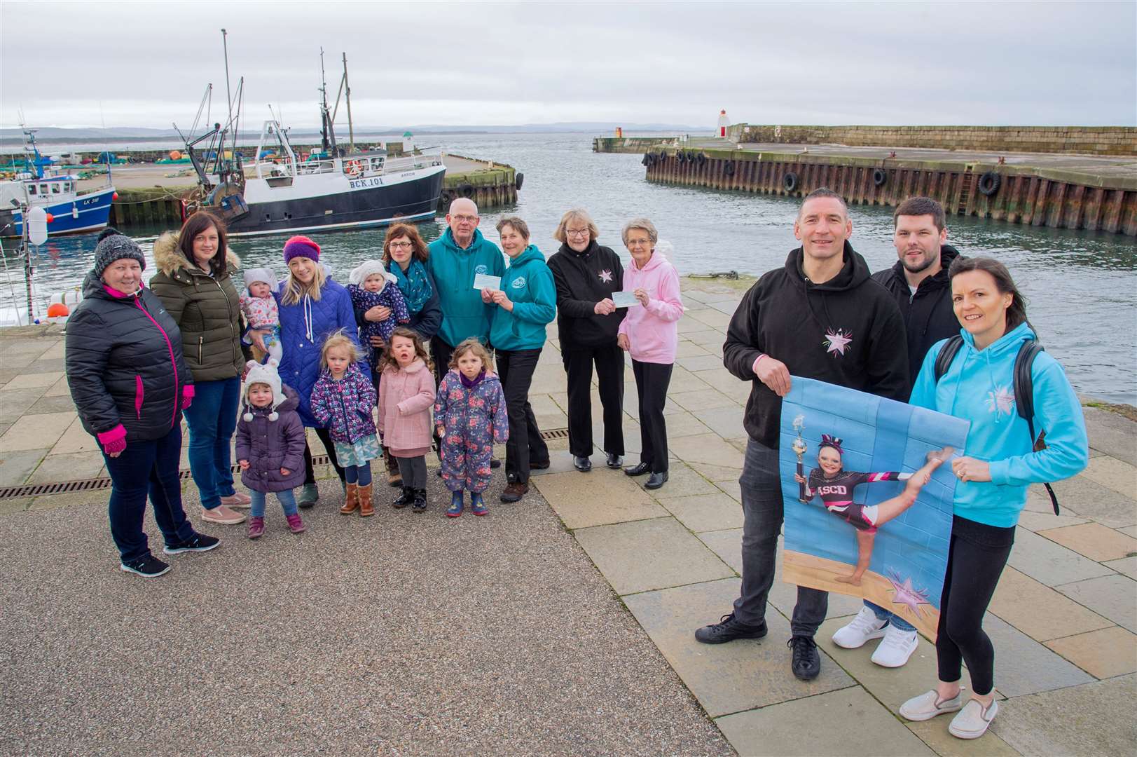 Holding a picture of Abbie Main, whose memory served as inspiration for creating the Abbie Sparkle Foundation charity, are parents Russell (left) and Tammy Main, alongside Burghead Boxing Day Swim president Jamie Campbell. Also pictured are members of the Burghead Parents and Toddlers, and Burghead Coastal Rowing Club.