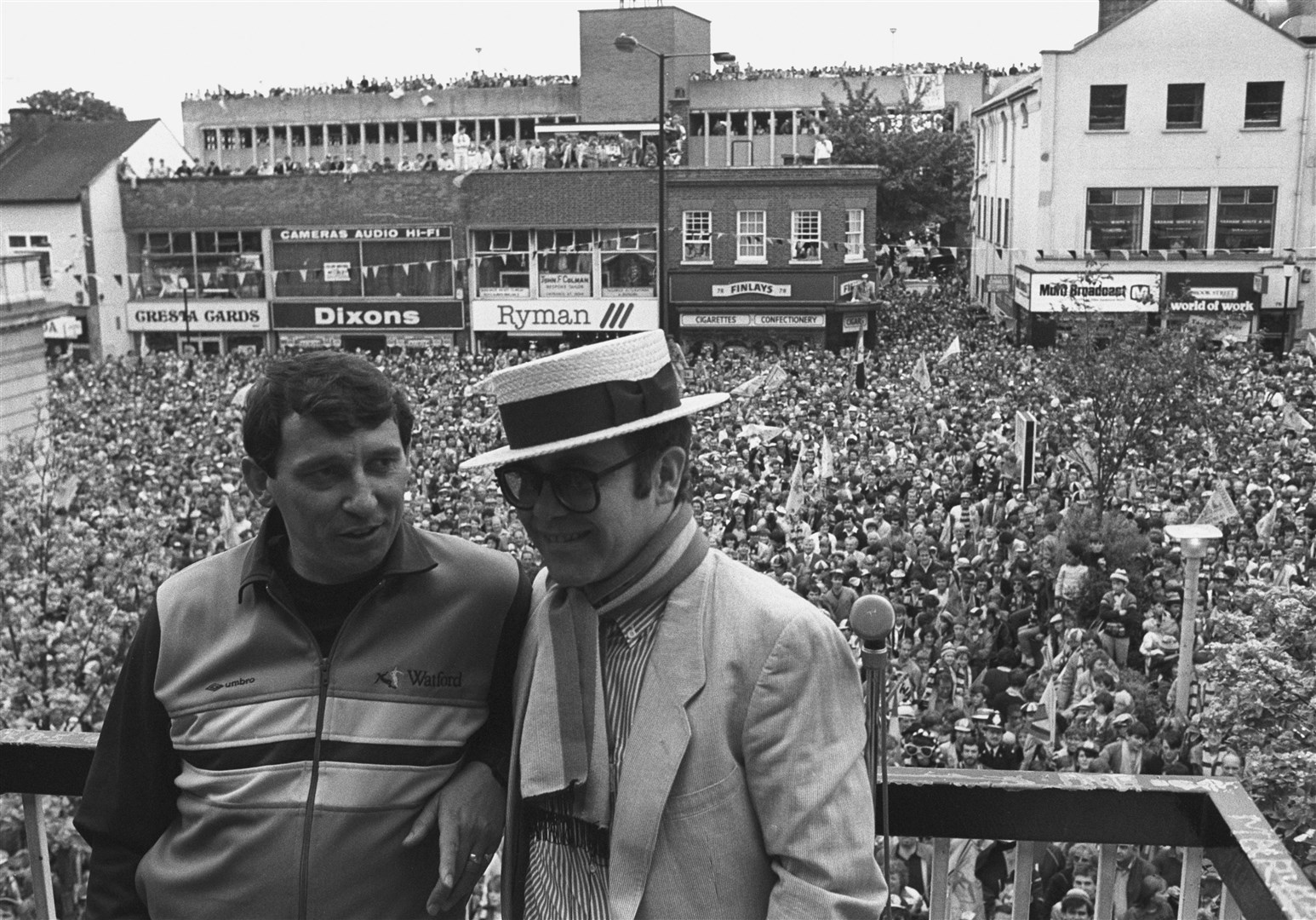 Sir Elton John, wearing the club scarf, with team manager Graham Taylor on a balcony overlooking a crowd of well wishers (PA)