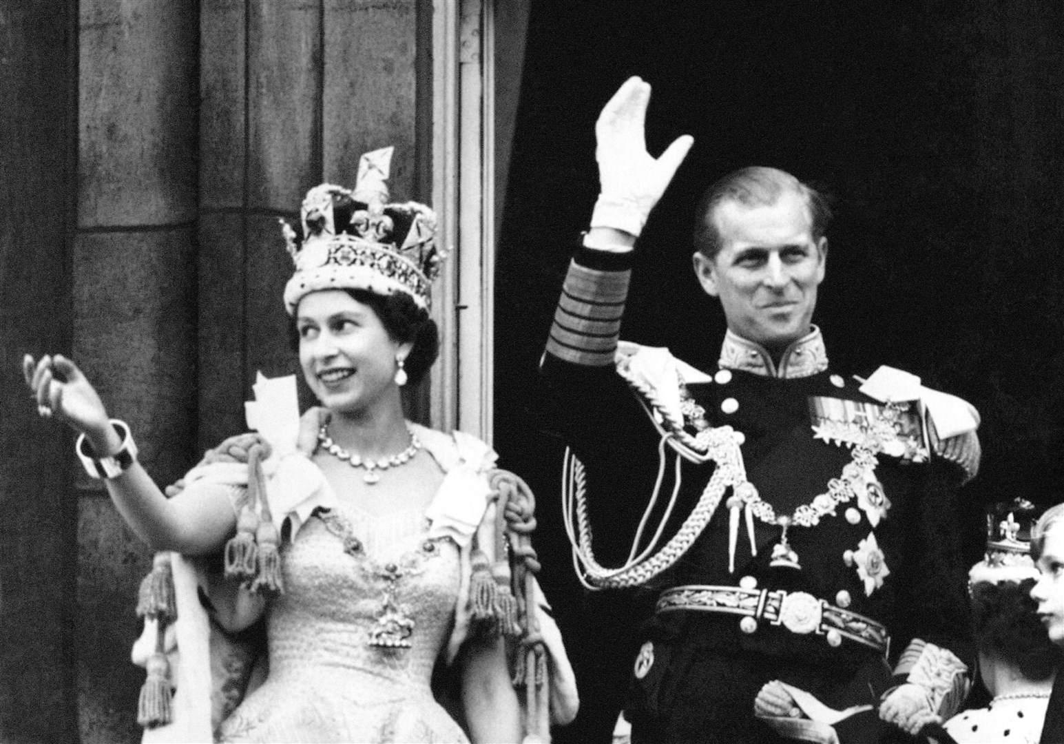 The Queen, wearing the Imperial State Crown, and the Duke of Edinburgh, dressed in uniform of Admiral of the Fleet, wave from the balcony to the onlooking crowds at the gates of Buckingham Palace after the coronation (PA)