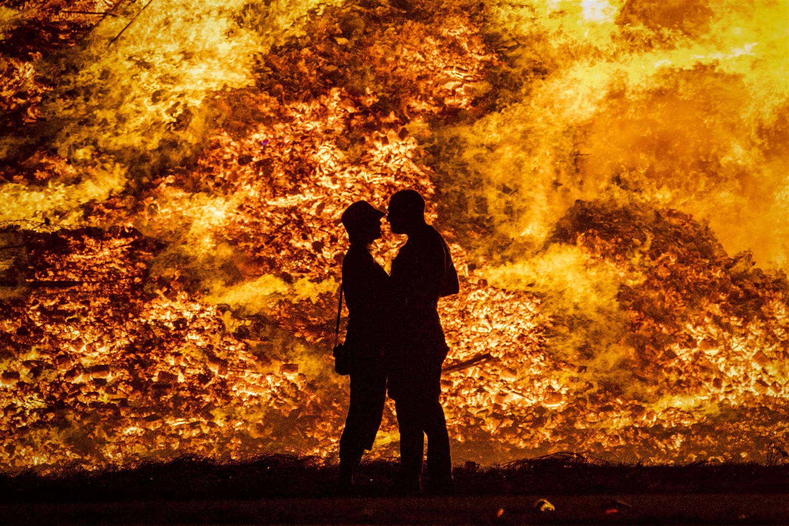 A couple embrace in silhouette at Craigyhill loyalist bonfire in Larne, Co Antrim (Liam McBurney/PA)