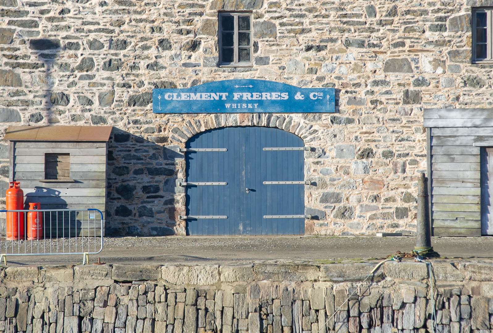 Un signe français, "Clement Freres & Cie - Whisky", a été placé sur un bâtiment faisant face au port et un auvent en bois ajouté à l'extérieur.  Image: Daniel Forsyth.