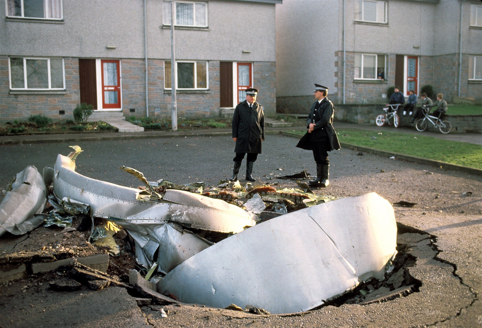 Police officers stand among debris after the explosion (PA)