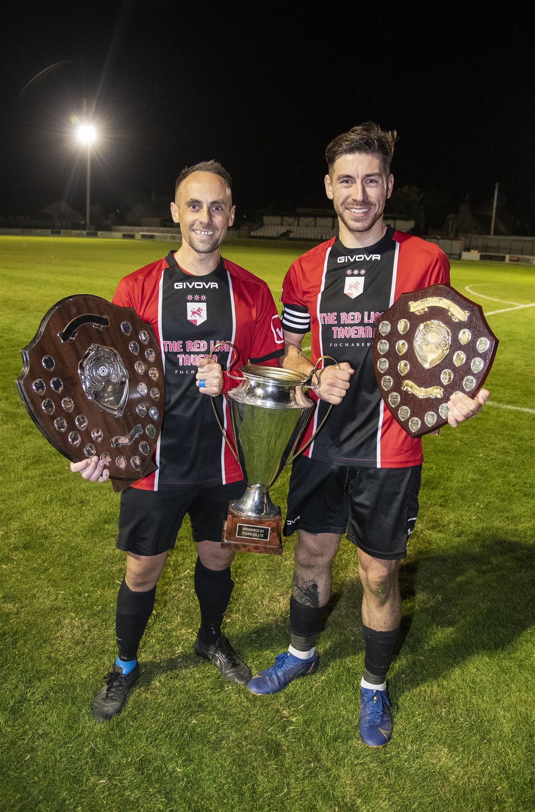 Gary Burchell (left) and captain Ben Stewart with the three trophies won by FC Fochabers this campaign. Picture: Becky Saunderson