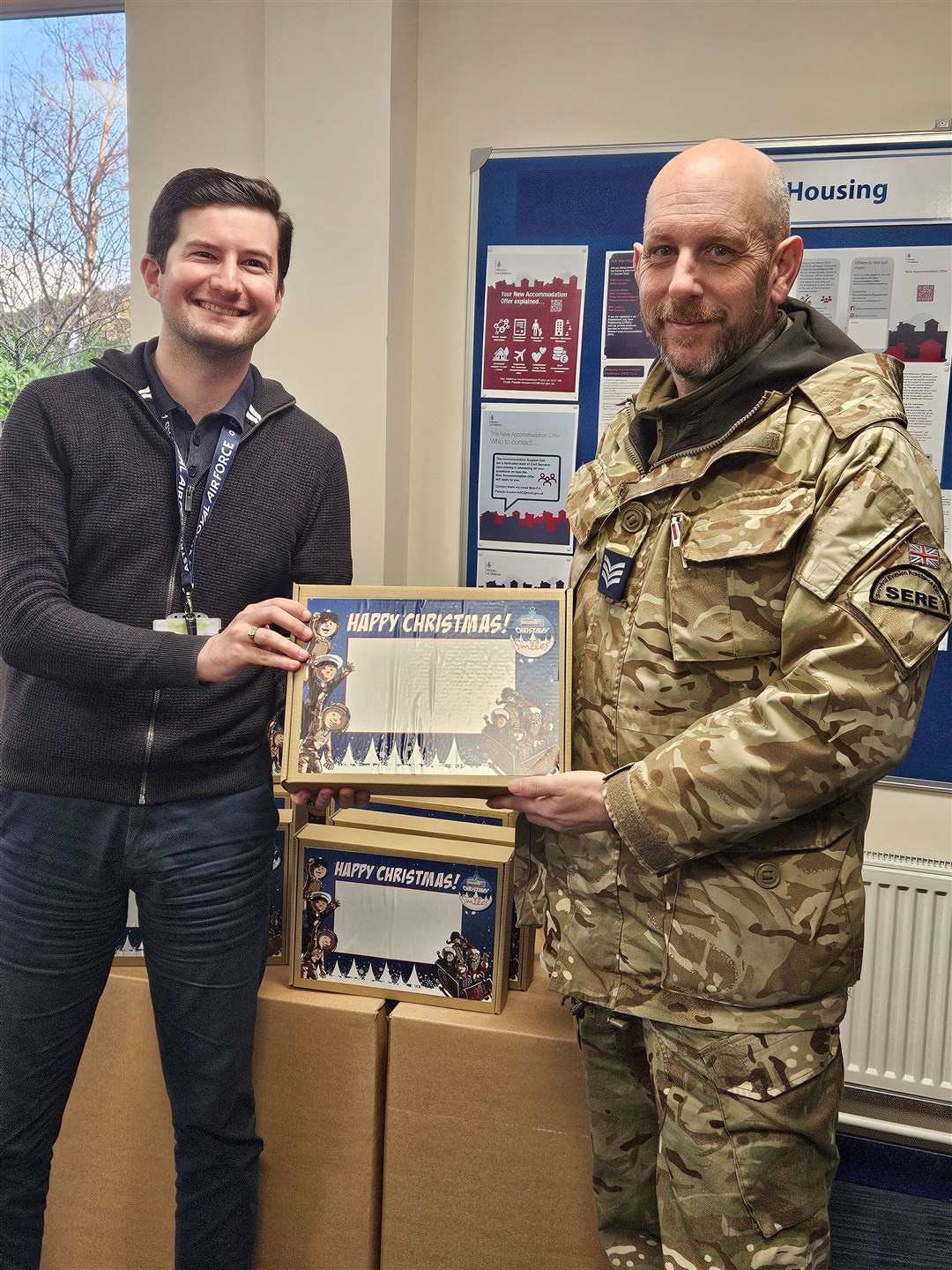 Chris, RAF Lossiemouth support clerk, hands a box to a local dad for his children.