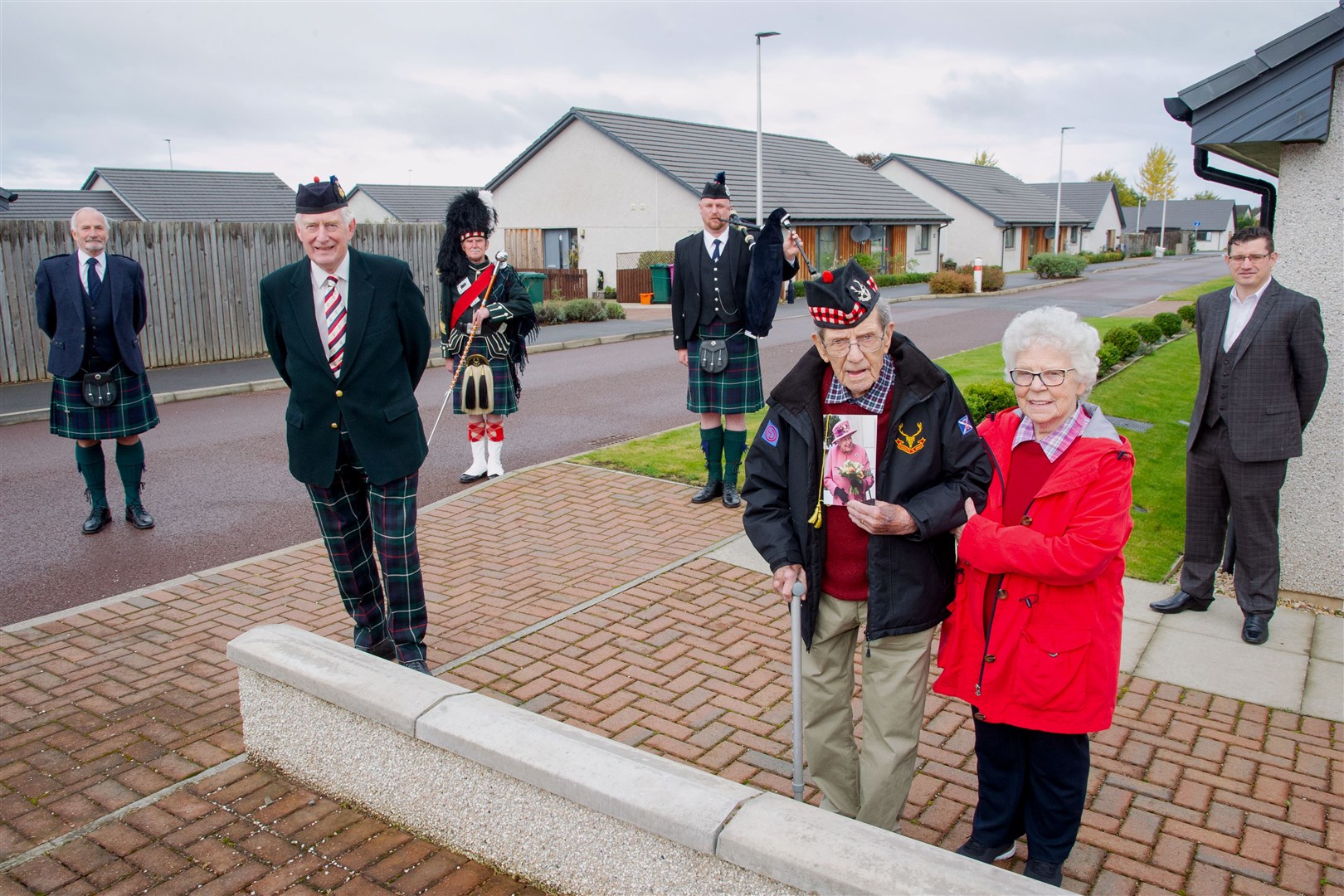 Forres Pipe band chairman John Channon, Major General Seymour Monro CBE, drum major Mike Munro, pipe sergeant Johnathan Scott, Donald and Helen Smith, and Councillor Aaron McLean celebrating Don's 100th birthday on Macrae Court.