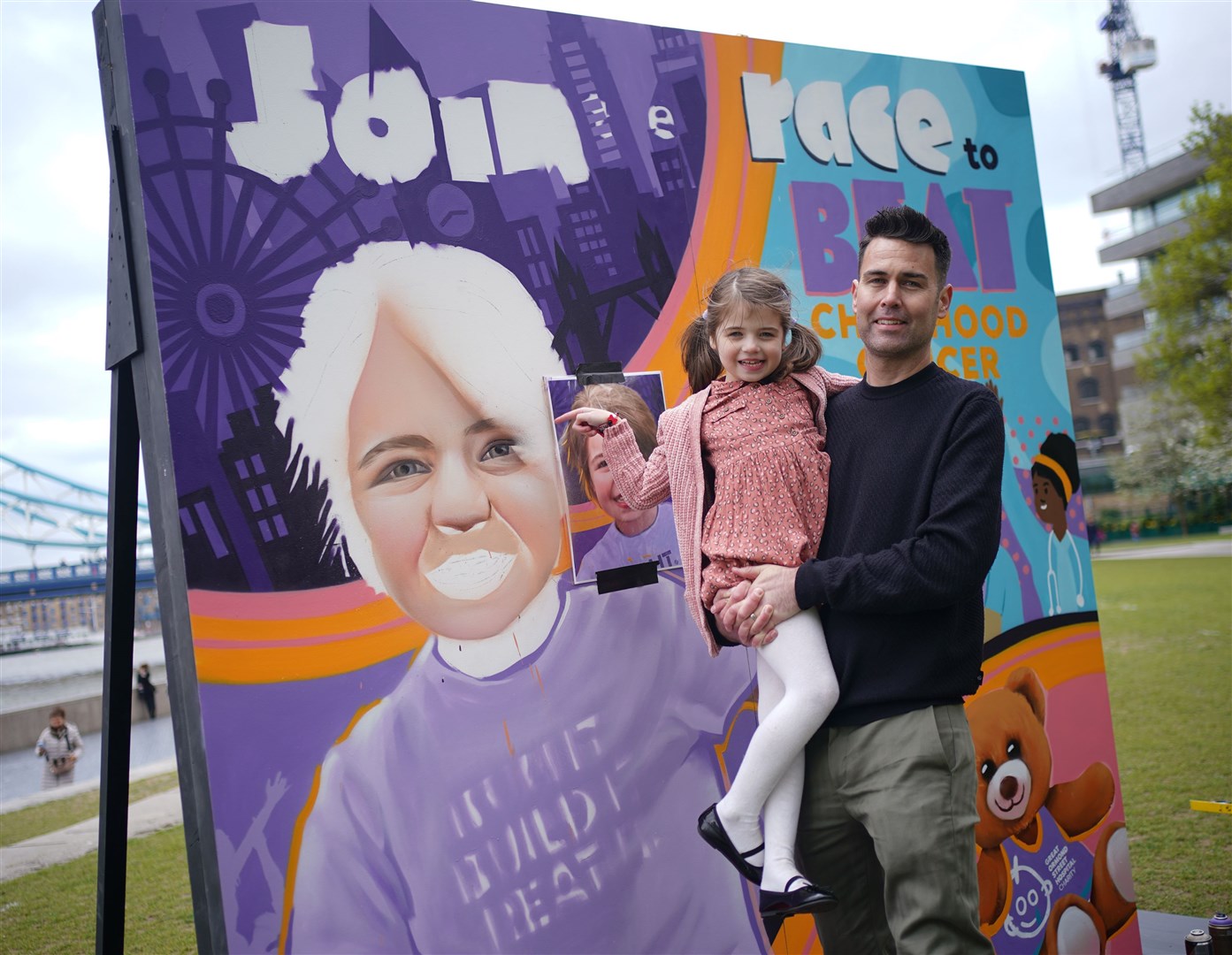 Six-year-old Sienna Halls with her father Gareth next to the mural at Potters Fields Park in London (Yui Mok/PA)