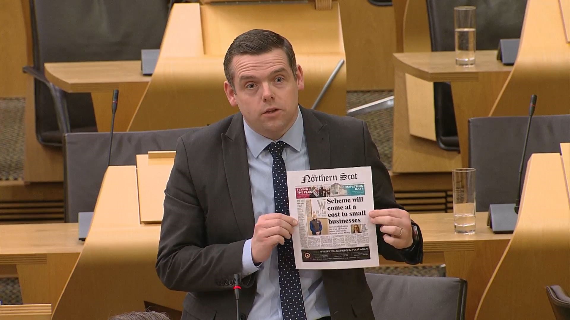 Douglas Ross holds up the front page of The Northern Scot in the Scottish Parliament.