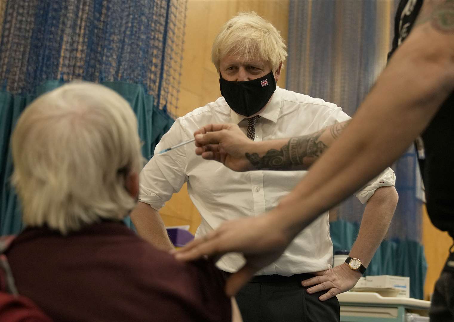 Prime Minister Boris Johnson watches as Nitza Sarner, 88, receives a Pfizer booster vaccination at the Little Venice Sports Centre in west London (Matt Dunham/PA)