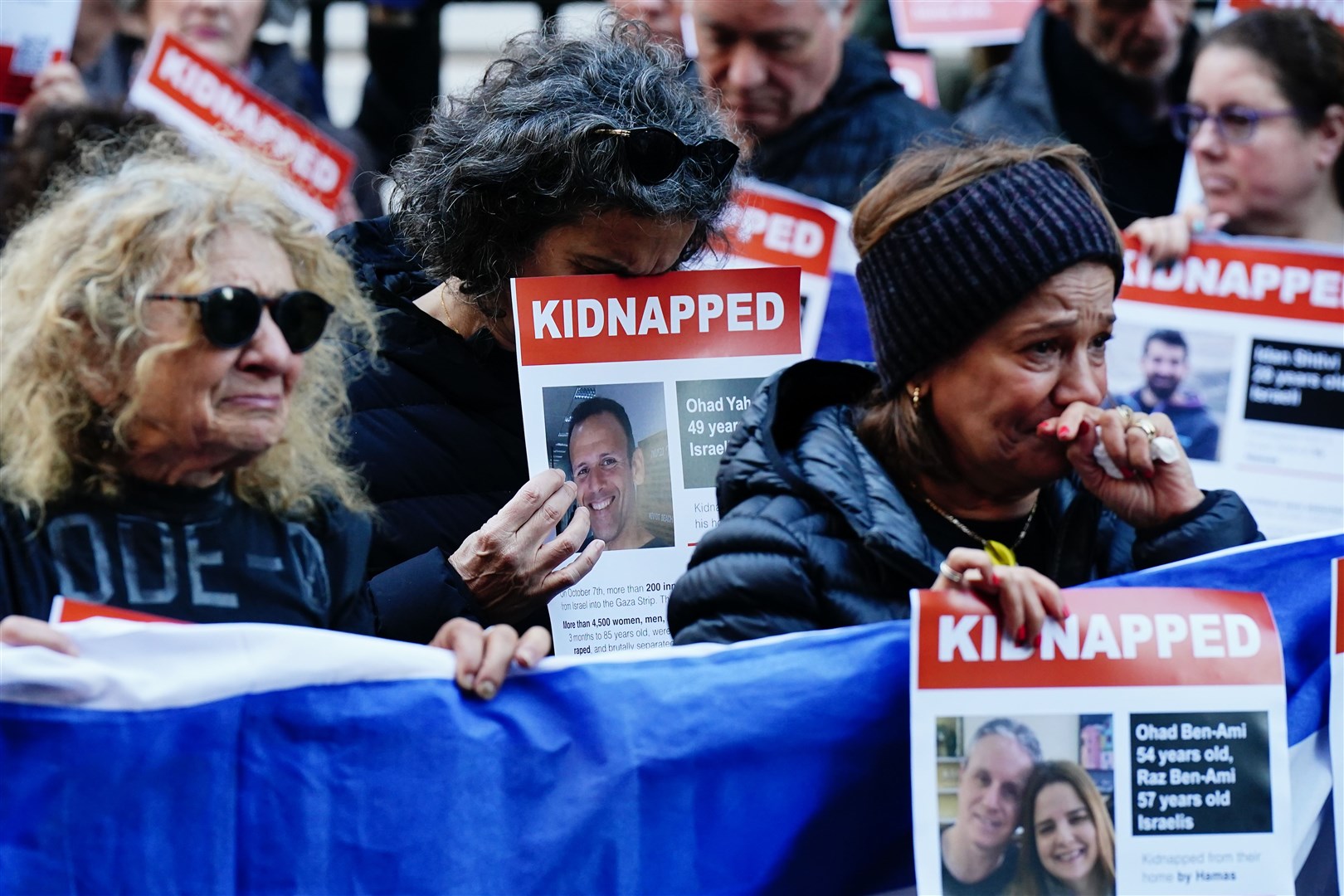 People hold up posters bearing the names and faces of those kidnapped (Aaron Chown/PA)