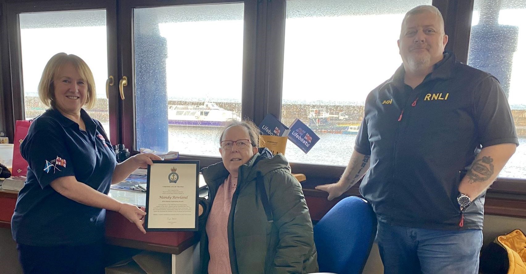 Mandy Rowland (centre) is presented her Certificate Of Thanks by Buckie RNLI Lifeboat Operations Manager Anne Scott and coxswain David Grant. Picture: RNLI/Lorna Cameron