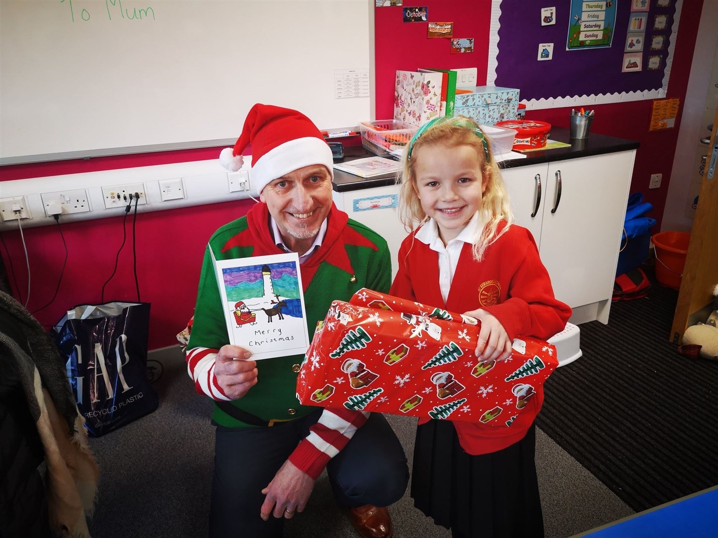 Manager Doug Mackenzie presents Evie Souter (6) with her prizes after winning a competition to design MP Douglas Ross' Christmas card.
