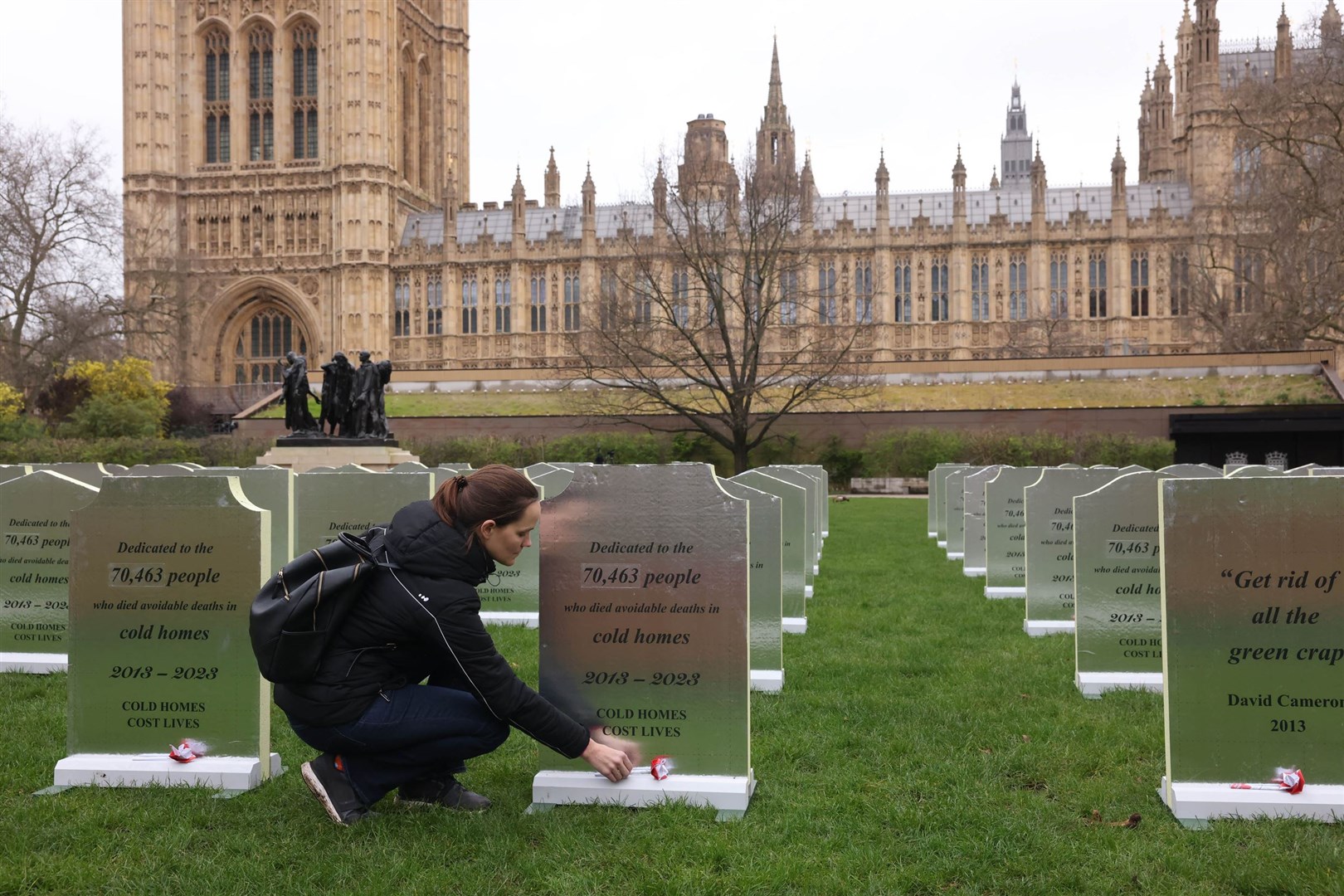 A Greenpeace activist lays a flower on one of the ‘headstones’ outside the Palace of Westminster (Alex McBride/Greenpeace/PA)