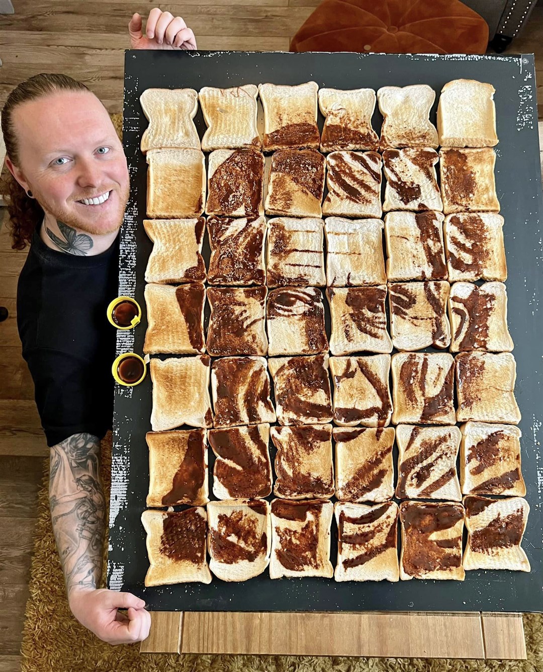 Nathan Wyburn with his portrait of the King using Marmite and 42 slices of toasted bread (PA)