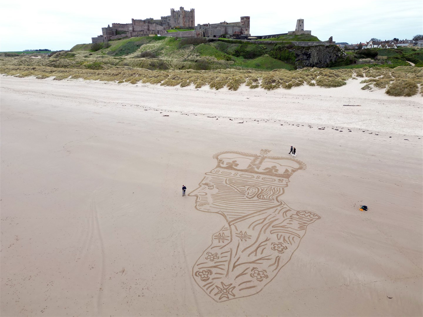 Sand artist Claire Eason puts the finishing touches to a 90ft by 65ft sculpture of Charles on Bamburgh beach in Northumberland (Owen Humphreys/PA)