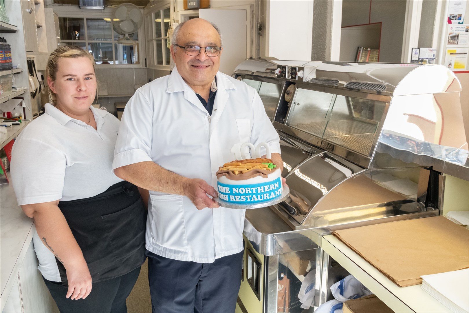 Amy Moir and Michael Miele with a specially made cake to celebrate the shop's 100th anniversary. Picture: Beth Taylor