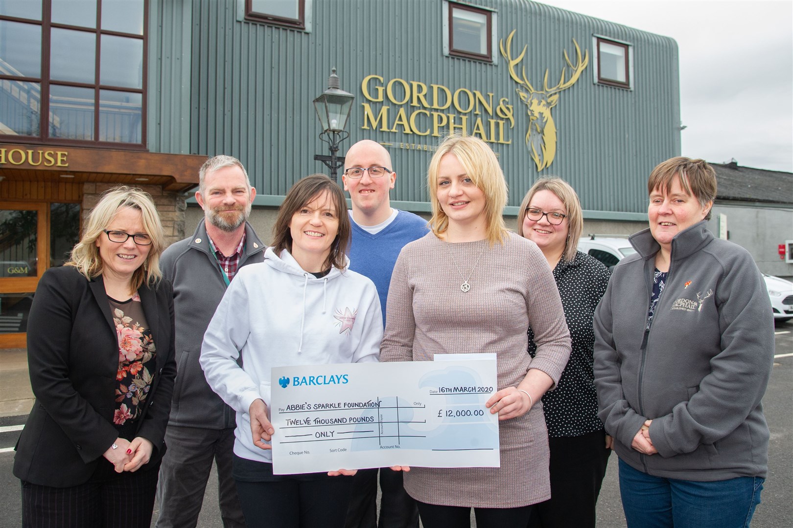 Jodie Clayton, HR generalist at Gordon & MacPhail, hands over a cheque for £12,000 to Tammy Main, of Abbie's Sparkle Foundation, surrounded by staff. Picture: Daniel Forsyth.