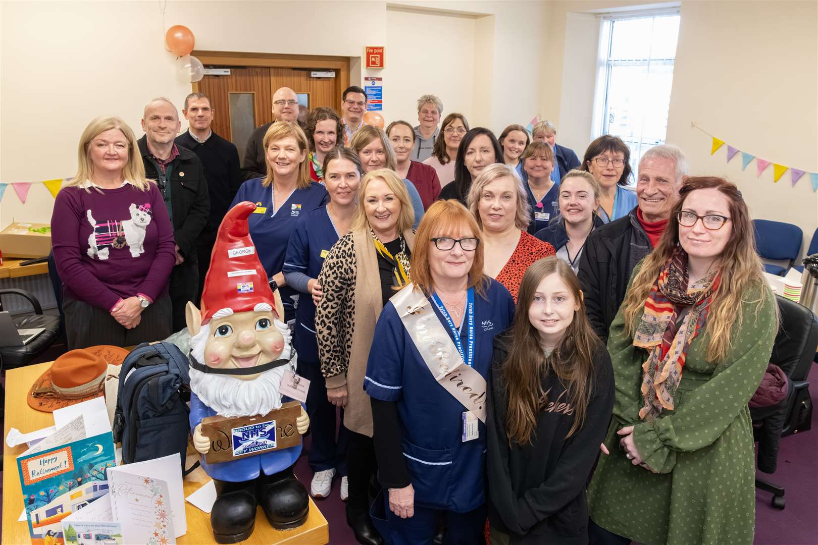 Trish Bury with her granddaughter Olivia, George the gnome and family and colleagues at her retirement celebration. Picture: Beth Taylor