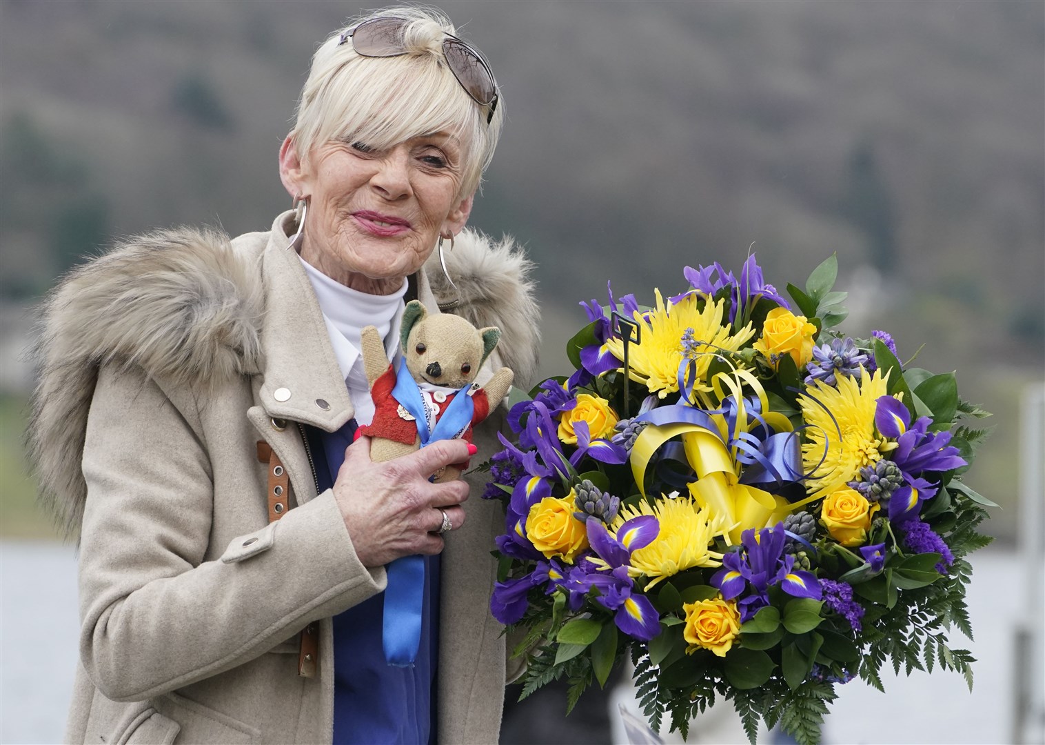 Gina Campbell, the daughter of world water speed record holder Donald Campbell, holds a bunch of flowers at Coniston Water during an event to mark the 100th anniversary of his birth (Owen Humphrey/PA)